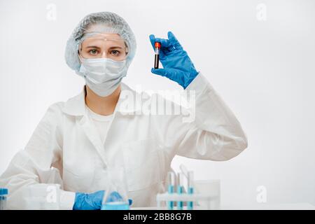 Arzt in Schutzuniform mit Maske zur Aufnahme der Blutprobe mit Coronavirus Stockfoto