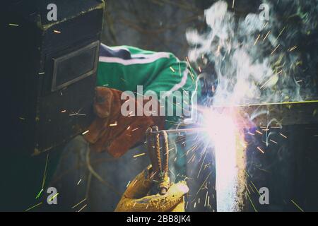 Nahaufnahme des Menschen mit Schweißmaske bei Schweißarbeiten mit Funken rundum Stockfoto