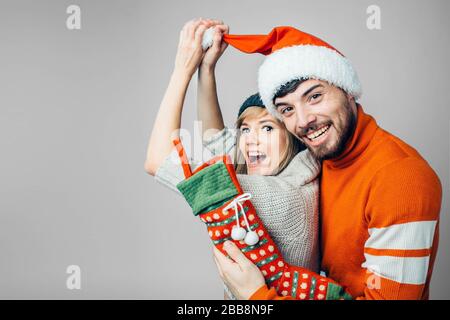 Junger bärtiger Mann und fröhliche Frau isoliert über den Hintergrund. Funnyfestliche Menschen in roter weihnachtskleidung. Lustige junge Familie posiert auf der Kamera. Neu Stockfoto