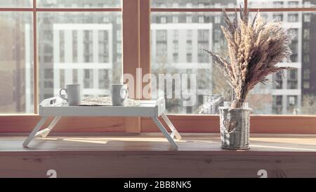 Zwei weiße Tassen auf Serviertisch mit Blumentopf auf Fensterschweller Stockfoto