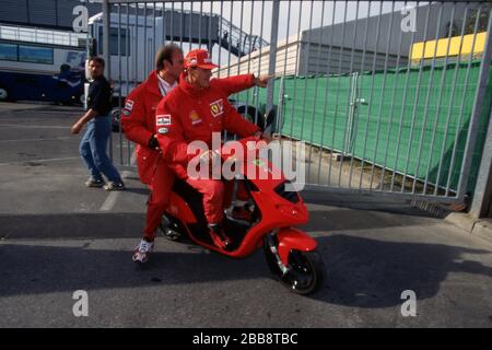 firo: Formel 1, Saison 1997 Sport, Motorsport, Formel 1, Archiv, Archivbilder Team Ferrari (1996-2006) Michael Schumacher, Deutschland, war von 1991 bis 2006 und 2010 bis 2012 Formel-1-Fahrer, Schumacher war 7, sieben Mal, Formel 1, Weltmeister, deutscher Nationalhelden, brachte Formel 1 nach Deutschland, Einer der größten Deutschen, die 1. Saison bei Ferrari Michael Schumacher, ganze Zahl, auf einem Roller, fährt neben der Strecke Stockfoto