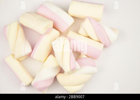 Marshmallow mehrfarbig. Meringue Marshmallows in einem grünen Becher auf hellem Hintergrund. Bunte Farbtöne auf weißem Hintergrund. Marshmallow fällt ab Stockfoto