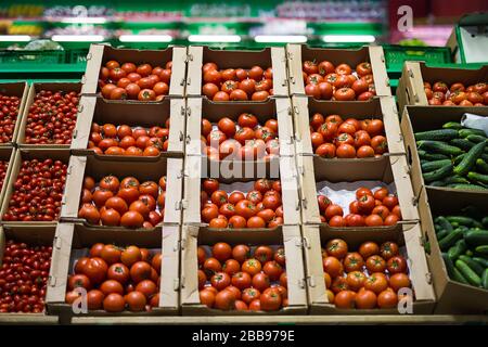 Schöne rote Tomaten in Kartons, zum Verkauf auf einem Marktregal Stockfoto
