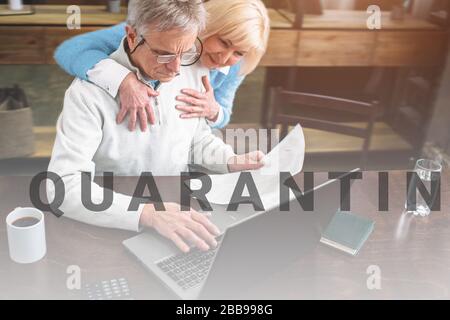 Schönes Bild von altes Ehepaar. Er sitzt am Tisch und arbeiten, während Sie ihn umarmte. Close Up. Schnittansicht Stockfoto