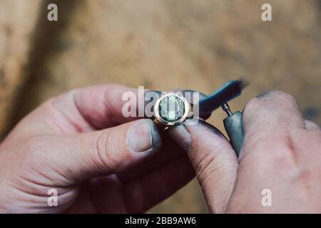 Nahaufnahme der Hände des Goldschmieds, der an einem Ring in seiner Werkstatt arbeitet Stockfoto