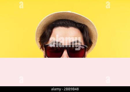 Mann in Sonnenbrille und panamahut hält ein leeres Banner, Sommerbillard, Mock-up-Bild Stockfoto
