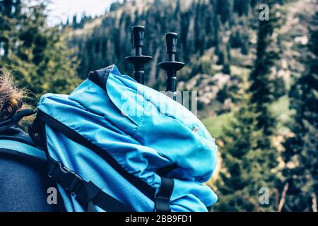 Mann, der in den Bergen mit einem großen blauen Reisesacksack wandert. Reisender Männer Trekking während seiner Reise. Reisen, Menschen, Sport und gesundes Lifestyle-Konzept Stockfoto