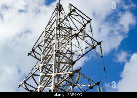 Hochspannungs-Elektrizitäts-Pylone und Übertragungsleitungen am blauen Himmel und Wolken Hintergrund. Power Towers und ihre Silhouetten gegen die Stockfoto