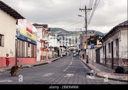 OTAVALO, ECUADOR - 28. JULI 2018: Eine unebene Straße mit Bergen im Hintergrund. Stockfoto