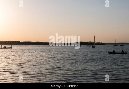 MADISON, WISCONSIN - 07. MAI 2018: Silhouettenansicht von Menschen, die auf dem Lake Mendota Kanufahren. Stockfoto
