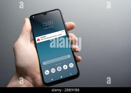 Quarantäne-Breach-Warnmeldung auf Smartphone, das von männlicher Hand gehalten wird. Ratschläge, um in Quarantäne zu Hause zu bleiben, um die Ansteckung zu stoppen. Pandemie, Gesundheitswesen, Techn Stockfoto