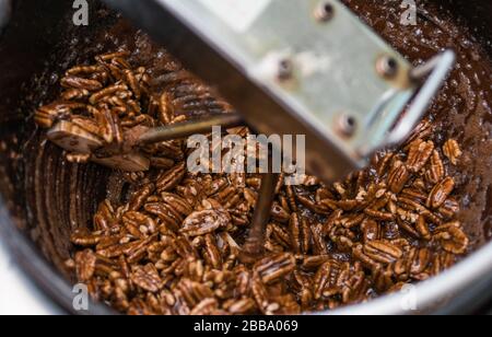 Nahaufnahme des Garvorgangs, um Zimtzucker glasierte geröstete Pekannüsse zu erzeugen. Stockfoto