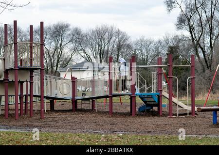 Hanover Park, Illinois, USA. Ein alleinstehender Mann, der trotz eines Nutzungsverbots auf eine freie Gruppe von Spielgeräten in einem öffentlichen Park zugreift. Stockfoto