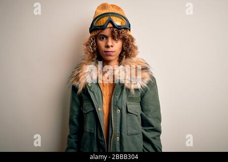 Junge afroamerikanische Skifahrerin mit lockigen Haaren, die Schneesportkleidung trägt und Skigrille skeptisch und nervös ist und wegen des Problems auftauchend ist. Neg Stockfoto