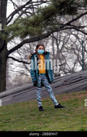 Ein junges Mädchen trägt ihre Maske bei einem Ausflug mit ihrer Familie im Central Park in New York, USA. März 2020. Stadt. Die großen New Yorker haben die Anleitung, wie sie zu Hause bleiben sollen, immer wieder aufgehütet, aber sie machen sie auch draußen, um frische Luft und Erholung zu genießen, während sie soziale Distanzierungsrichtlinien praktizieren. Credit: Adam Stoltman/Alamy Live News Stockfoto