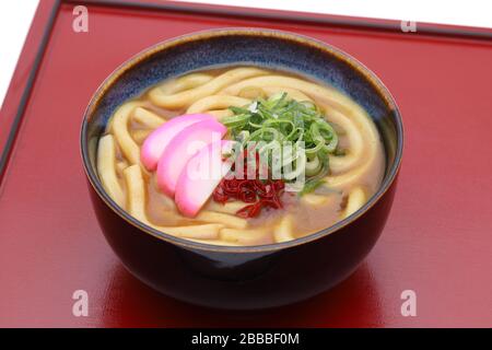 Japanische Curry-Eudon-Nudeln in einer Keramikschale auf rotem Tablett Stockfoto