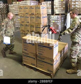 Soldaten der Michigan National Guard unterstützen das Michigan Department of Health and Human Services bei der Montage und dem Beladen kritischer persönlicher Schutzausrüstung, wie Handschuhe, Schutzhandschuhe und Gesichtsschutz, am 18. März 2020. Nach der Verpackung liefert MDHHS die Lieferungen an verschiedene öffentliche Gesundheitsbehörden. (USA Foto der Nationalgarde von Sgt. James Bennett) Stockfoto