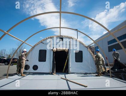 Die Flugzeuge des 103. Civil Engineer Squadron stellten am 27. März 2020 zwei Alaskan Small Shelter Systems in der Newington VA Clinic in Newington, Connecticut auf. Die Connecticut Air National Guard Airmen bauten diese Schutzräume mit Umweltkontrolleinheiten, Stromverteilungsplatten und Energieerzeugung für den möglichen Einsatz von Patienten als Reaktion auf die COVID-19-Pandemie (USA Foto der Air National Guard von Staff Sgt. Steven Tucker) Stockfoto