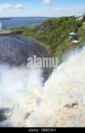 Blick von oberhalb der Montmorency Falls, während Wasser in ein Bassin stürzt, das sich im Hintergrund in den Sankt-Lorenz-Strom entleert, Parc de la Chute-Montmorency in der Nähe von Quebec City, Quebec, Kanada Stockfoto