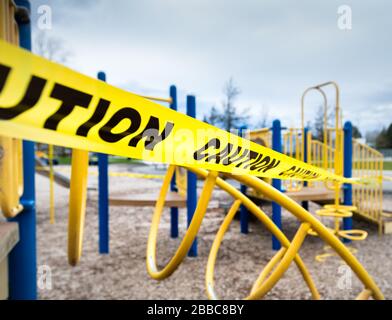 Gelbes Warnband um Klettergeräte auf einem geschlossenen öffentlichen Spielplatz während der Zeit der Coronavirus Covid-19-Pandemie Stockfoto