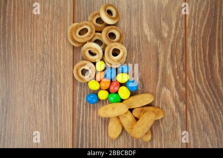 Snacks Backwaren Plätzchen Bagels Schokoladenwürfel für Tee Kaffee Milchsaft auf einem Holztisch Hintergrund. Die Ansicht von oben Stockfoto