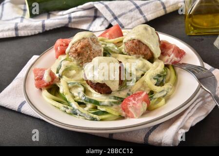 Zucchini Nudeln mit Basilikumpesto Alfredo Soße und Fleischbällchen Stockfoto