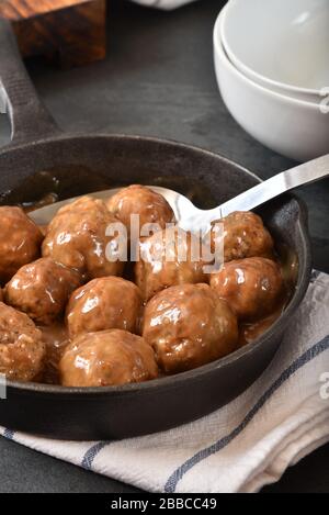 Schwedische Gourmet-Fleischbällchen in einem gusseisernen Skillet mit brauner Gravy und einem Servierlöffel Stockfoto