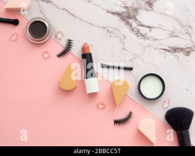 Weibliche Mode Beauty Blogger Arbeitsbereich. Makeup Tools, Kosmetikprodukte, isoliert auf zweifarbigem Marmor- und pinkfarbenem Hintergrund mit Kopierraum f Stockfoto