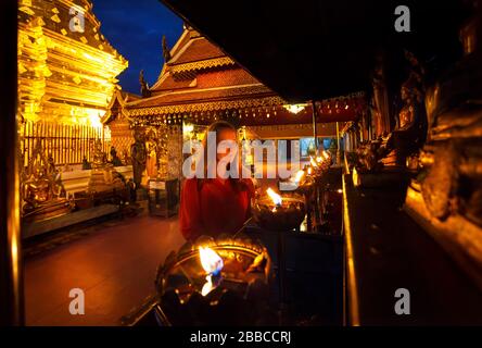 Frau touristischen Blick auf Gebet Kerze leuchtet bei buddhistischen Tempel Doi Suthep nachts in Chiang Mai, Thailand Stockfoto