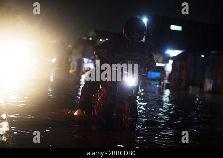 Bandung Regency, Indonesien. März 2020. Ein Motorradfahrer überquert die Straße bei einem Hochwasser in Bandung regency, West Java, Indonesien, 30. März 2020. Überschwemmungen aufgrund starker Regenfälle. (Foto von Agvi Firdaus/INA Photo Agency/Sipa USA) Credit: SIPA USA/Alamy Live News Stockfoto