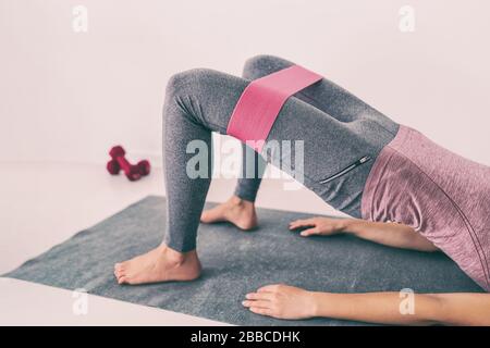 Fitness zu Hause Widerstandsfähigkeit elastische Bänder Bein Workout Übung für Oberschenkel und glutes Hüftbrücke Entführung. Yoga fit Frau Krafttraining auf dem Boden der Wohnung. Pinkes Accessoire. Stockfoto