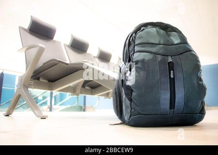 Der Rucksack steht auf dem Boden vor einer Reihe leerer Sitze in einem Flughafenterminal. Flughafen-Interieur ohne Menschen. Stockfoto