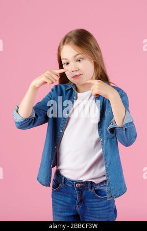 Kleines Mädchen mit Sonnenbrille, das rosafarbenen Kaugummi vor einem hellvioletten Hintergrund aufbläst. Stockfoto