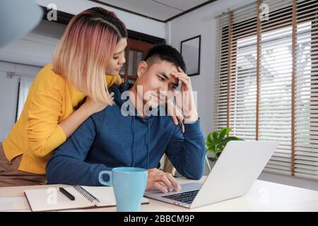 Asiatische Freundin Ermutigung Freund von Stress während auf home Haushalt auf dem Laptop im Wohnzimmer in der Heimarbeit Stockfoto