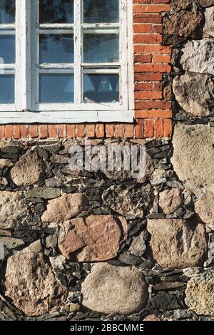 Bruchstück der verwitterten Steinmauer der mittelalterlichen Kirche mit einem später erbauten Teil des Fensters Stockfoto