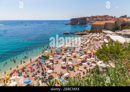 DUBROVNIK, KROATIEN - 10. AUGUST 2016: Tagsüber im Sommer Blick auf den Strand von Banje, die Adria und die Altstadt von Dubrovnik. Große Mengen o Stockfoto