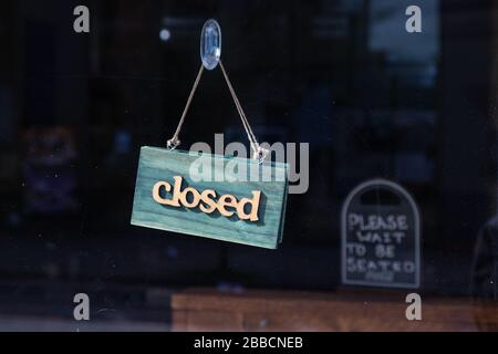 Ein Schild in einem Restaurant mit der Aufschrift "geschlossen". Im Hintergrund wird eine Meldung mit der Aufschrift "Bitte warten Sie, bis er sitzt" angezeigt. Während des Londoner Coronavirus eingenommen Stockfoto