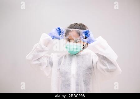 Junge Krankenschwester mit Einweg-Overall mit sterilen Handschuhen Vorbereitung Pflege der Pandemie 2019 Coronavirus 2019-nCoV. Stockfoto