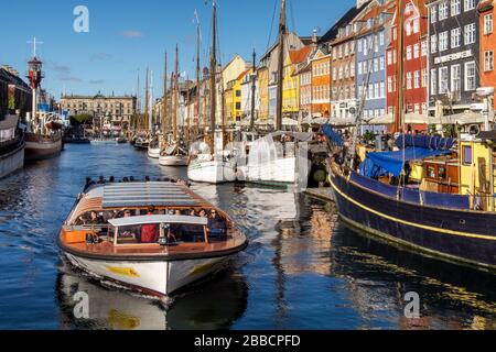 Ausflugsboot auf dem Nyhavn-Kanal und der Promenade mit seinen bunten Fassaden, Hafengebiet aus dem 17. Jahrhundert, Kopenhagen, Dänemark Stockfoto