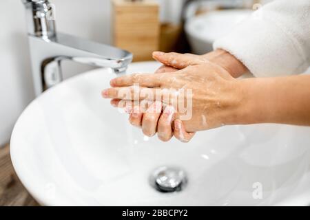 Frau wäscht die Hände gründlich mit einer Seife im Badezimmer, kümmert sich um Hygiene, Nahaufnahme der Hände Stockfoto