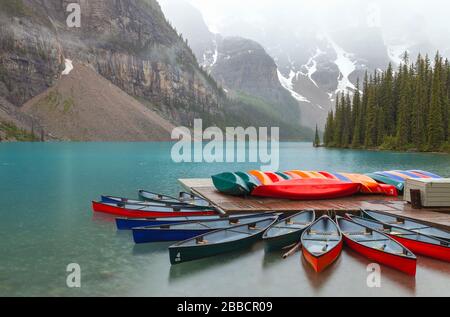Bunte Kanus am Moraine Lake, Banff National Park, Alberta, Kanada, an einem regnerischen Sommertag. Stockfoto