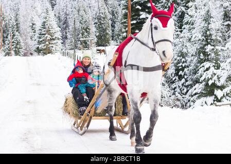 Eine Familie, die ein Pferd reitet, das in Weihnachtsgarb gekleidet ist Stockfoto