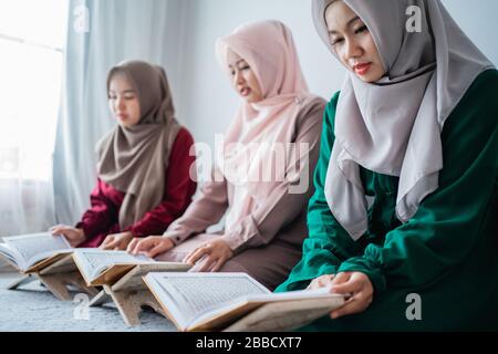 Drei muslimische asiaten lesen und lernen das heilige Buch des Al-Quran zusammen auf dem Boden im Raum sitzen Stockfoto