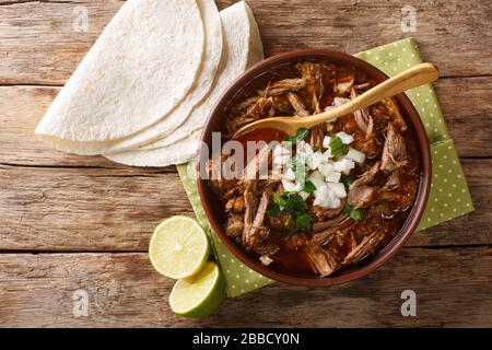 Mexikanischer Stil langsam gekochtes Rindfleisch, Anschnitt Birria de res, serviert mit Limette und Tortilla Closeup in einer Schüssel auf dem Tisch. Horizontale Draufsicht von oben Stockfoto
