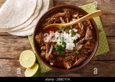Birria ist ein mexikanisches Gericht, ein würziger Eintopf, der traditionell aus Ziegenfleisch in einer Schüssel auf dem Tisch zubereitet wird. Horizontale Draufsicht von oben Stockfoto