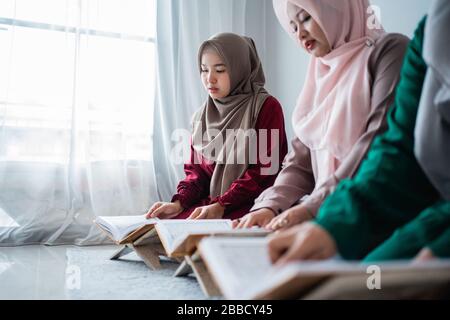 Drei muslimische asiaten lesen und lernen das heilige Buch des Al-Quran zusammen auf dem Boden im Raum sitzen Stockfoto