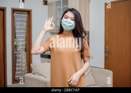 Porträt einer fröhlichen und gesunden jungen Frau asian mit medizinischer Maske. Pandemie 2019 Coronavirus COVID-19-Konzept. Stockfoto