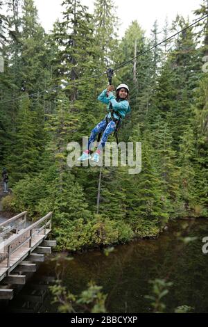 Ein junges Mädchen reitet eine Zipline auf dem Grouse Mountain, North Vancouver, British Columbia, Kanada. Stockfoto