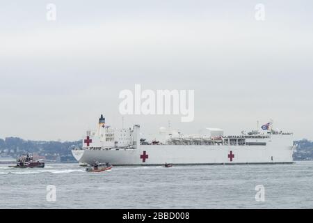 NEW YORK, NY - 30. MÄRZ: Das Militär-Sealift-Kommando-Lazarettschiff USNS Comfort (T-AH 20) wird von der US-Küstenwache, der New Yorker Polizeibehörde und den Anlagen der New Yorker Feuerwehr begleitet, wenn das Schiff in New York City, 30. März 2020 ankommt. Komfort, der zur Unterstützung der COVID-19-Reaktionsbemühungen des Landes eingesetzt wird und als Überweisungskrankenhaus für nicht-COVID-19-Patienten dient, die derzeit in Landkrankenhäusern eingeliefert werden. So können Krankenhäuser in Landhäusern ihre Bemühungen auf COVID-19-Fälle konzentrieren. Eine der Missionen des Verteidigungsministeriums ist die Verteidigungsunterstützung von Zivilbehörden. DoD wird unterstützt Stockfoto