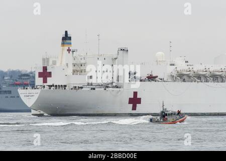 NEW YORK, NY - 30. MÄRZ: Das Militär-Sealift-Kommando-Lazarettschiff USNS Comfort (T-AH 20) wird von der US-Küstenwache, der New Yorker Polizeibehörde und den Anlagen der New Yorker Feuerwehr begleitet, wenn das Schiff in New York City, 30. März 2020 ankommt. Komfort, der zur Unterstützung der COVID-19-Reaktionsbemühungen des Landes eingesetzt wird und als Überweisungskrankenhaus für nicht-COVID-19-Patienten dient, die derzeit in Landkrankenhäusern eingeliefert werden. So können Krankenhäuser in Landhäusern ihre Bemühungen auf COVID-19-Fälle konzentrieren. Eine der Missionen des Verteidigungsministeriums ist die Verteidigungsunterstützung von Zivilbehörden. DoD wird unterstützt Stockfoto